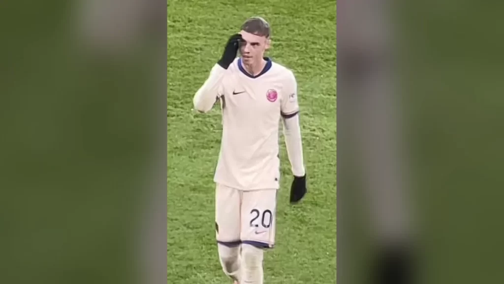 Cole Palmer on the pitch in Chelsea's cream third kit with the number 20, wearing black gloves and touching his forehead, during the Premier League match away at Leicester City in November 2024.